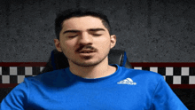 a man is wearing a blue adidas shirt