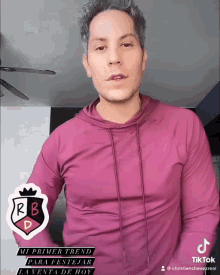 a man wearing a pink shirt with a rb logo on the front