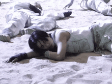 a man laying in the sand with his head on his arms