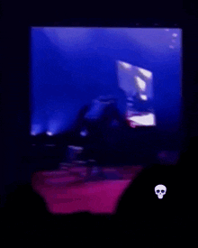 a man is kneeling down on a stage in front of a purple p logo