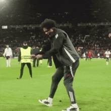 a man is dancing on a soccer field with a man in a yellow vest with the number 71 on it