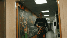 a man in a black shirt with the number 15 on the back walks down a hallway