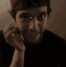 a man with a beard is holding his hand to his chin and making a face .