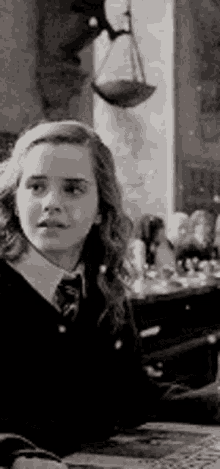 a young girl in a school uniform is sitting at a table in front of a scale .