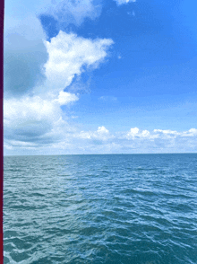 a large body of water with a blue sky and white clouds in the background