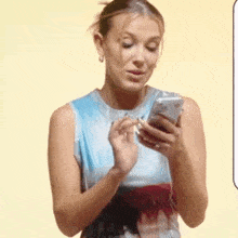 a woman in a blue dress is holding a cell phone .