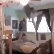 a room with a bed and a window with a person standing on the ceiling .