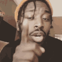 a man with dreadlocks is pointing at the camera