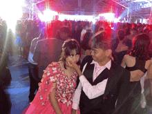 a girl in a pink dress is touching a man 's face at a party