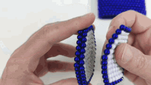 a person is holding a piece of blue and white beads .