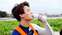 a young man is drinking a bottle of yogurt from a white bottle .