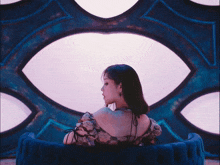 a woman is sitting on a blue couch in front of an eye