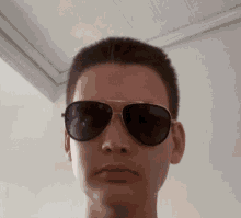 a young man wearing sunglasses looks at the camera with a serious look on his face