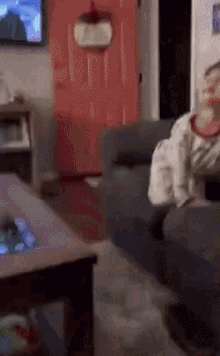 a person is sitting on a couch in a living room with a tv on the wall .