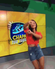 a woman dancing in front of a sign that says chapa tus taba