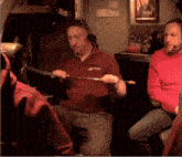 a man wearing a red shirt that says safety holds a stick