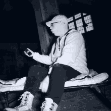a man in a white hoodie is sitting on a bed