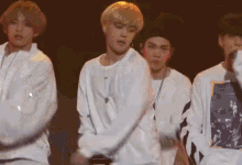 a group of young men are standing next to each other on a stage and dancing .