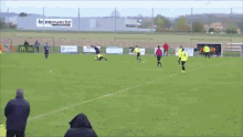 a group of people are watching a soccer game on a field and one of them is wearing a yellow jersey with the number 7 on it