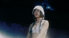 a woman wearing a white hat and braids is standing in the dark
