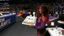 a woman is holding a cake in front of a sign that says new amite
