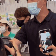 a man wearing a mask is taking a picture of a group of people .