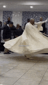 a man in a long white dress is dancing in front of a group of men with the caption @crente_aranha