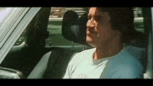 a man is sitting in the driver 's seat of a car and smiling .
