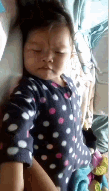 a baby wearing a polka dot pajama is sleeping