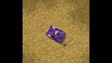 a purple tank is sitting on a sandy field