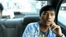 a man is sitting in the back seat of a car and laughing while wearing a shirt that says " haha "
