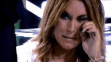 a woman wipes her face with her hand while wearing earrings