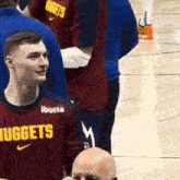 a man wearing a shirt that says nuggets is standing on a basketball court