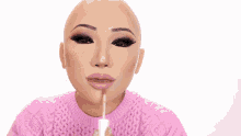 a woman wearing a pink sweater is applying makeup