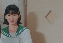 a girl in a sailor uniform is looking at her reflection in a square hole in the wall .