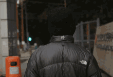 a person wearing a black jacket that says the north face on the back