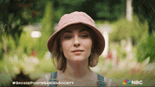 a woman wearing a pink hat with the words grossepointegardensociety written on the bottom
