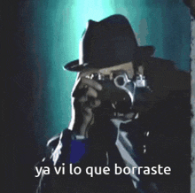 a man in a fedora is taking a picture with the words ya vi lo que borraste behind him