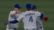 three blue jays players hugging each other on the field