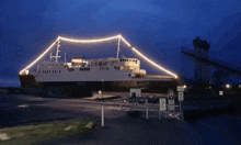a large ship is lit up at night and has a no parking sign in front of it