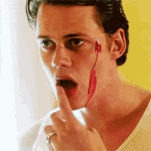 a man with blood on his face is holding his finger to his lips