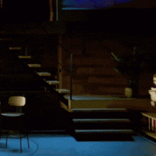 a woman in a red shirt is standing in front of stairs