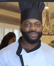 a man with a beard and a chef 's hat is standing in a kitchen .