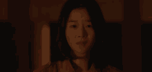 a close up of a woman 's face in a dark room looking at the camera .