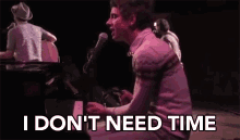 a man singing into a microphone while playing a piano with the words i don t need time below him