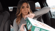 a woman in a car is holding a pizza box that says join to win