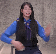 a girl with long hair wearing a blue shirt and a black vest