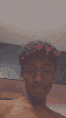 a shirtless young man wearing glasses and a crown of hearts on his head