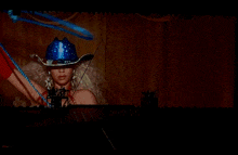 a woman wearing a blue cowboy hat is holding a blue ribbon