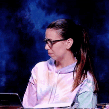 a woman wearing glasses is sitting at a desk with a laptop